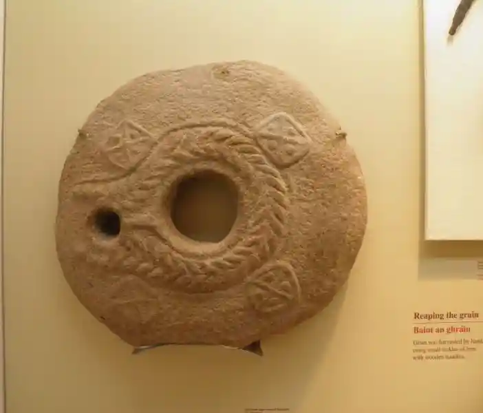 Circular stone with holes and crosses design and a wreath-like symbol